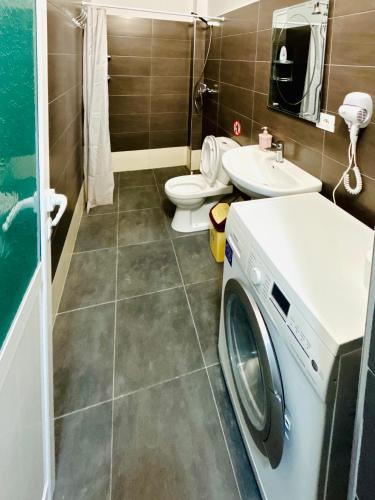 a bathroom with a washing machine and a toilet at Kristian apartments in Berat