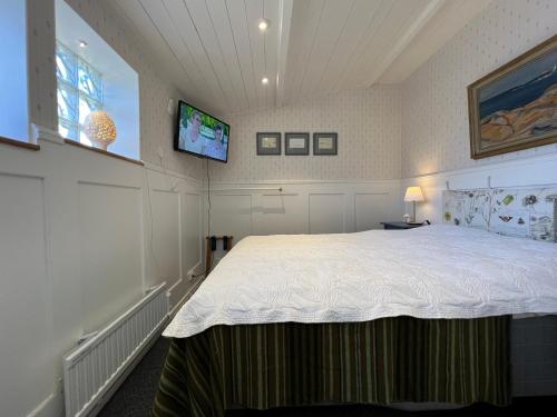 a bedroom with a large bed with a tv on the wall at Trädgårdscafé Pedalen B&B in Halmstad