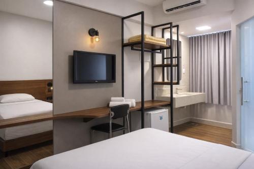 a room with a bed and a desk with a television at Premium Executive Hotel Itabira in Itabira
