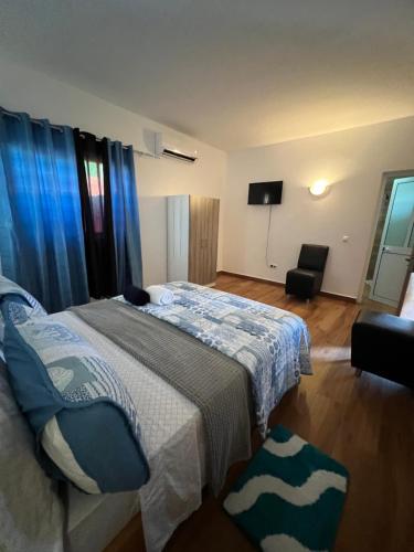 a bedroom with a bed with blue curtains and a television at Residência Águia in Praia