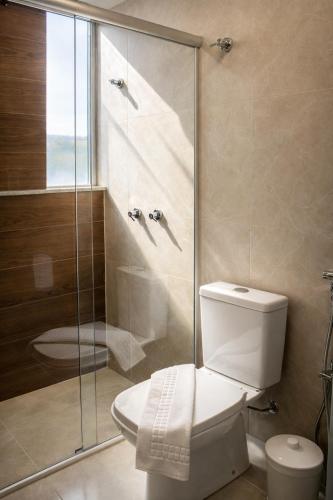 a bathroom with a toilet and a glass shower at Premium Executive Hotel Itabira in Itabira