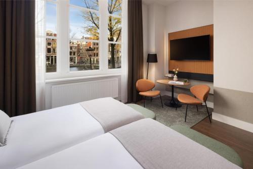 a bedroom with a bed and a tv and a table at NH City Centre Amsterdam in Amsterdam