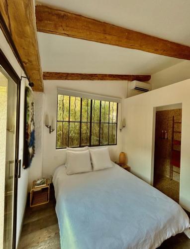 a bedroom with a large bed and a window at La mandarine in Ramatuelle