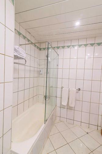 a white tiled bathroom with a shower and a tub at Dexon Roma Down Town Hotel in Hurghada