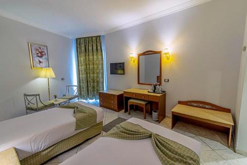 a hotel room with two beds and a mirror at Dexon Roma Down Town Hotel in Hurghada