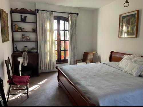 a bedroom with a bed and two chairs and a window at Hacienda Bugambilias Boutique Colonial in Cedro