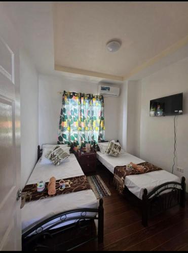 two twin beds in a room with a window at Rweydz Guest Inn Dorm in Tagbilaran City
