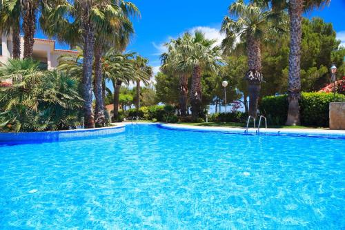 una piscina con palmeras en un complejo en UHC Costa Linda Family Complex, en Hospitalet de l'Infant