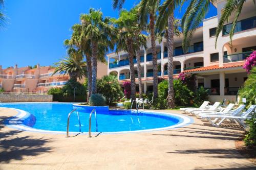 una piscina frente a un hotel con palmeras en UHC Costa Linda Family Complex, en Hospitalet de l'Infant