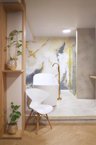 a bathroom with a white chair and a painting at Hotel Relaks Wellness & SPA in Karpacz