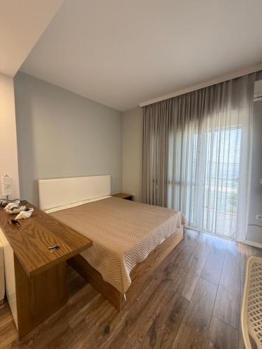 a bedroom with a bed and a large window at Beachfront Apartment Saranda in Sarandë