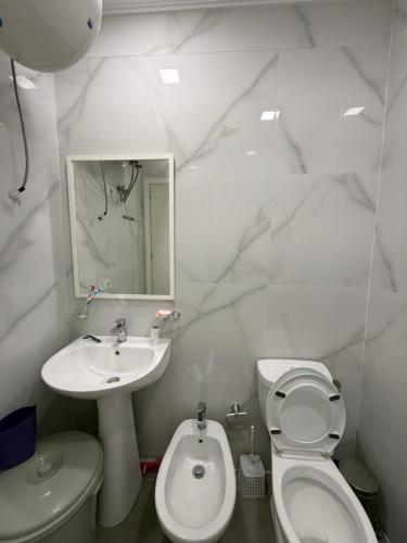 a bathroom with a sink and a toilet and a mirror at Beachfront Apartment Saranda in Sarandë