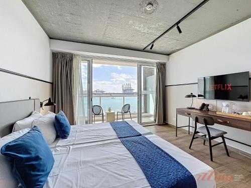 a bedroom with a large bed with a desk and a window at South 32 Hotel by Zzzing in Birżebbuġa
