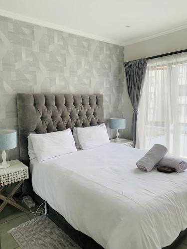 a bedroom with a large white bed with a large headboard at The Bridge at Montego in Fourways