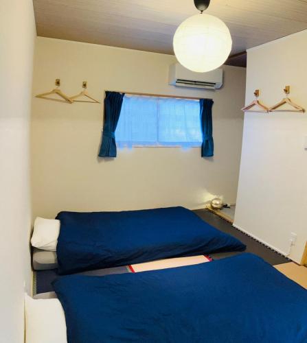 a bedroom with a blue bed and a window at 旅の宿 もはち Private Guesthouse MOHACHI in Tsuruoka