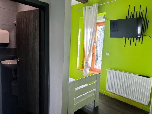 a bathroom with green walls and a sink and a television at Das Hostel Rijeka in Rijeka