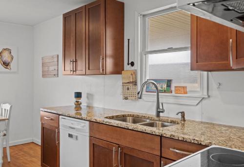 a kitchen with wooden cabinets and a sink at Central OBX Getaway with Pool and Sound Access in Nags Head