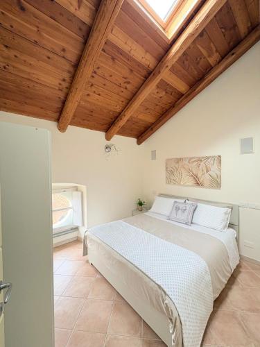 a bedroom with a large white bed with wooden ceilings at Dimora Faglietto in Rivarolo Canavese