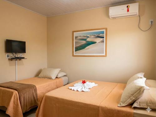 a room with two beds and a tv at Pousada Areias de Amaro in Santo Amaro
