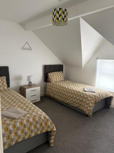 a attic bedroom with two beds and a window at Binghambelle in Bangor
