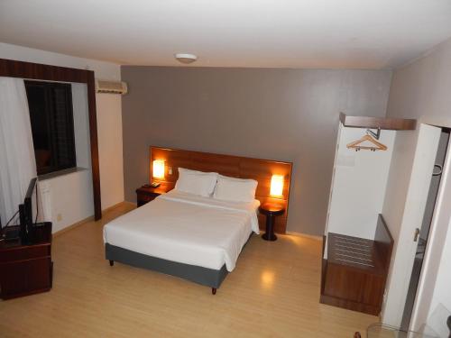 a bedroom with a white bed and two night stands at Prinz Apart Hotel in Joinville