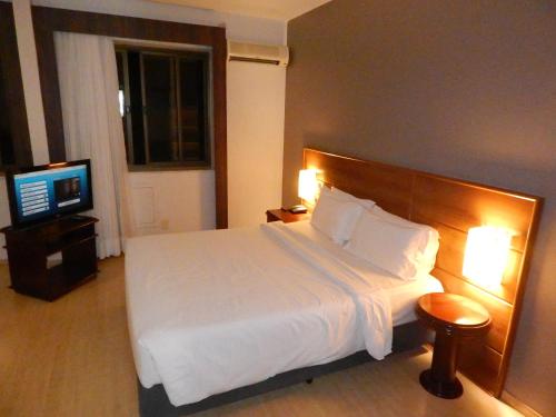 a bedroom with a large bed and a television at Prinz Apart Hotel in Joinville