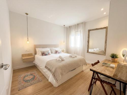 a bedroom with a bed and a table and a mirror at Casa Carmela Fuengirola in Fuengirola