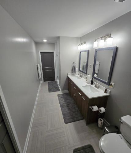 a bathroom with two sinks and two mirrors at Immaculate Vibes Sunset View Condo in Birmingham