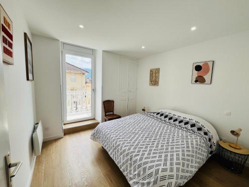 a bedroom with a bed and a large window at Le Vinois Climatisation 2 chambres balcon in Vinay