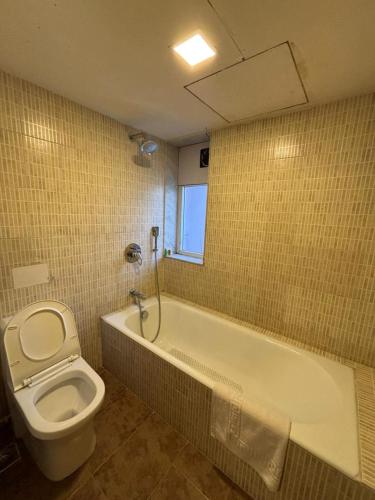 a bathroom with a toilet and a tub and a sink at Amazinn Hotel in Lonavala