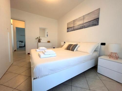 a bedroom with a large white bed with towels on it at Casa Chiaretto Piscina e Relax nel cuore di Moniga in Moniga