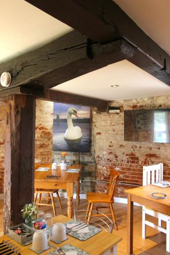 a dining room with tables and chairs and a swan on the wall at Yaxham Mill in East Dereham