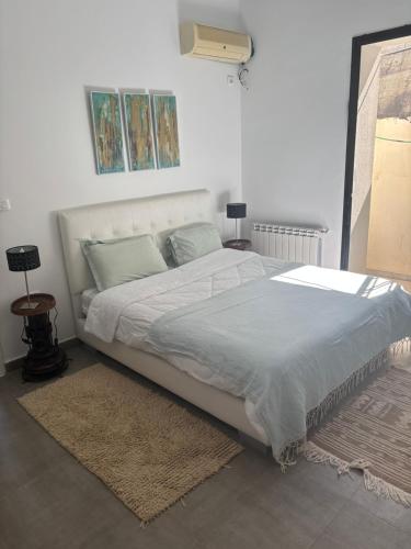 a bedroom with a large white bed with a rug at Work and Wave cosy studio at La Marsa in Douar el Hafey