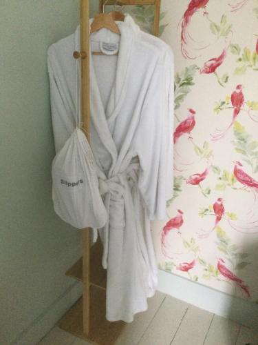 a white robe hanging on a rack in a room at Nether Dallachy Farmhouse in Banff