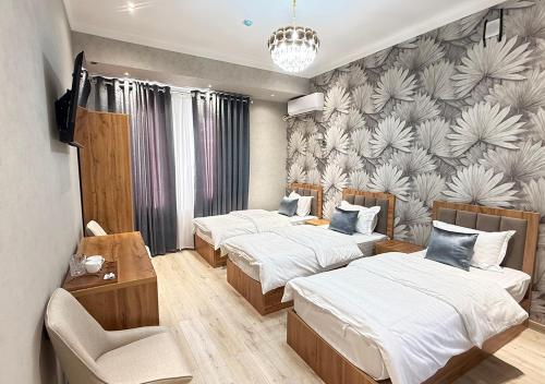 a bedroom with three beds and a wall with flowers at Amir Mumtoz Hotel in Bukhara