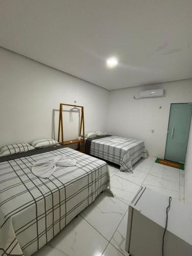 a room with two beds and a mirror in it at pousada palmeiras bhs in Barreirinhas