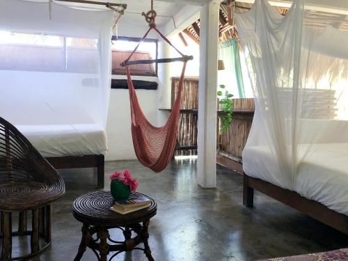 a room with two beds and a hammock at Una Posada Mas in Mazunte