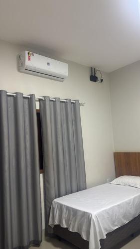 a bedroom with a bed with a gray curtain at Pousada e Hotel Mirasol in Mato Verde