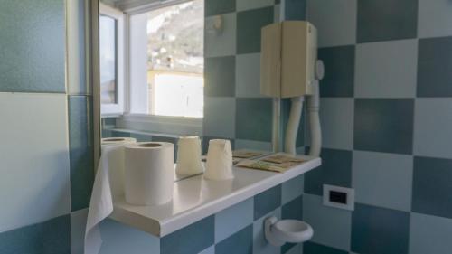 ein Badezimmer mit blau-weiß gefliesten Wänden und einem Spiegel in der Unterkunft Hotel Ideal in Sarche di Calavino