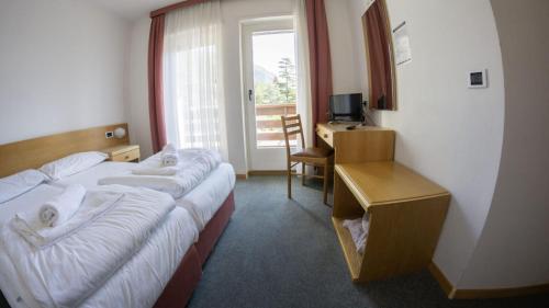 ein Hotelzimmer mit zwei Betten, einem Schreibtisch und einem Fenster in der Unterkunft Hotel Ideal in Sarche di Calavino