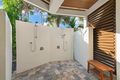 a bathroom with two showers and a wooden bench at Bentley Beach House in Sanibel