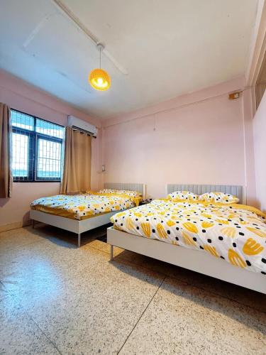 two beds in a room with yellow and white sheets at REHome in Bangkok