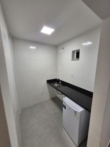 a white bathroom with a counter and a small refrigerator at Apart Suítes Praia Do Morro 5 a 7 dias e Barato in Guarapari