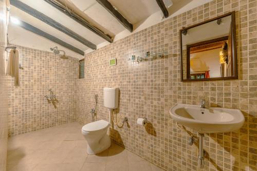 a bathroom with a sink and a toilet and a mirror at Little India Beach Cottages in Baga