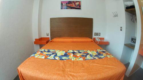 ein Bett mit einer orangefarbenen Bettdecke in einem Zimmer in der Unterkunft Hotel Yekkan in Huauchinango
