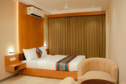 a hotel room with a bed and a chair at Hotel Bariz Perinthalmanna in Perintalmanna