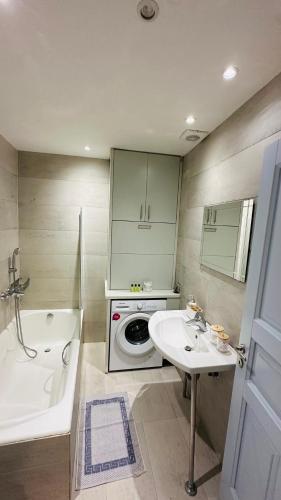 a bathroom with a tub and a sink and a washing machine at Mimoza Collection suites in Ornos