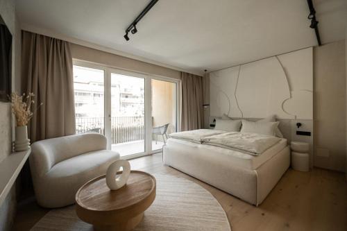 a bedroom with a bed and a chair and a table at Sonnen Resort in Naturno