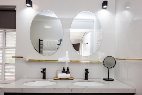 two sinks in a bathroom with two mirrors at Whispering Oaks Guest House in George