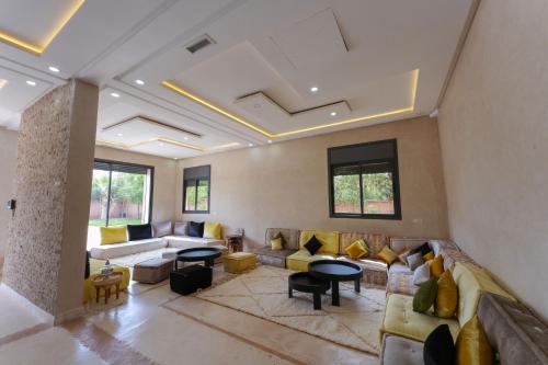 a living room with couches and tables and windows at Dar El Gharrabia villa entièrement privatisée in Amezrou